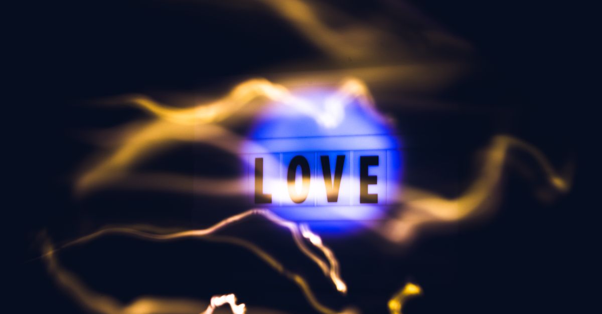 A conceptual abstract image featuring the word 'LOVE' illuminated with blue and yellow light streaks on a black background.